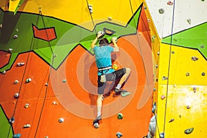 Man climber on artificial climbing wall in bouldering gym