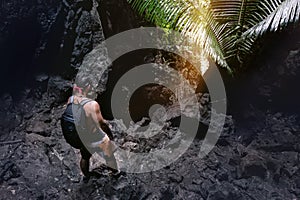 Man climber stands near cave or big rock