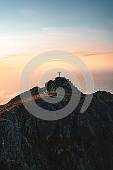 Man climber on the top of mountain traveling in Norway alone enjoying aerial view hiking outdoor traveler raised hands