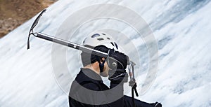 Man is climbing with ice ax on the glacier.