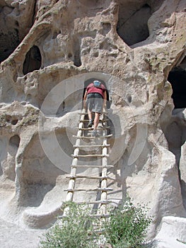 Man climbing ladder at cliff dwellings photo
