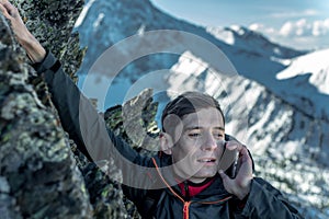 Man climbing the mountain to the top and talking on the phone. Communications and goal achievement in career