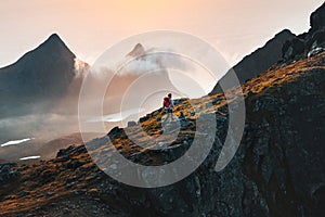 Man climbing mountains traveling in Norway tourist solo hiking in Lofoten islands outdoor traveler with backpack