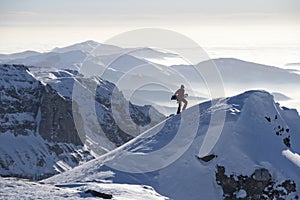 Man climbing a peak with snowboard