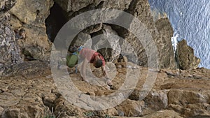 A man is climbing a rock wall with a red shirt