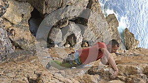 A man is climbing a rock wall with a rope around his waist