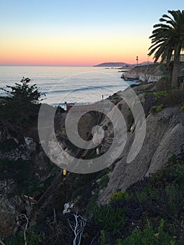 Man climbing stairs up cliff in Pismo Beach, California at sunset.