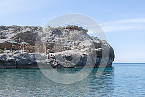 Man climbing on steep cliffs at the seaside in Greece