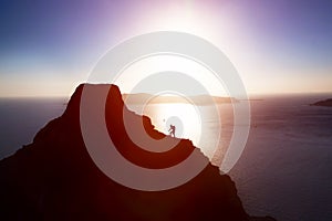 Man climbing up hill to reach the peak of the mountain over ocean.