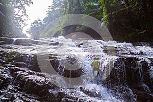 A man climbing in a waterfall in the tropical forest