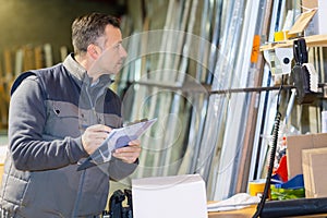 man with clipboard in factory preparaing parcel for despatch