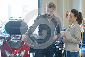 Man with clipboard looking at motorcycle