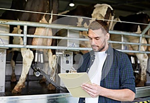 Man with clipboard and milking cows on dairy farm