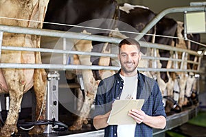 Man with clipboard and milking cows on dairy farm