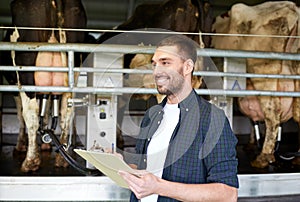 Man with clipboard and milking cows on dairy farm