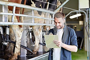 Man with clipboard and milking cows on dairy farm