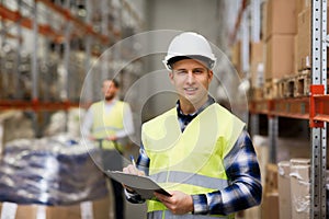 Man with clipboard in safety vest at warehouse