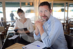 man with clipboard sat at table in cafe