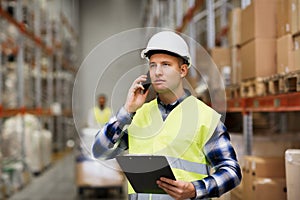 Man with clipboard and smartphone at warehouse