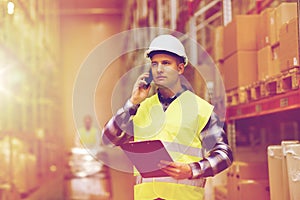 Man with clipboard and smartphone at warehouse