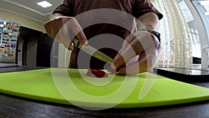 man close up wide angle cutting hot pepper on slice board