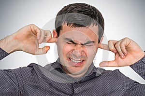 Man closes ears with fingers to protect from loud noise photo