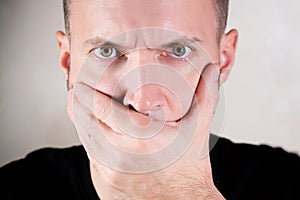 A man closes his mouth with his palm