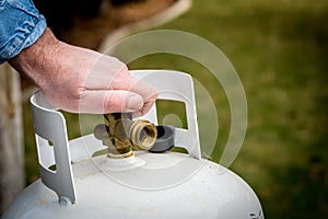 Man closes a knob on a propane tank