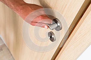 Man closing a light wood interior door photo