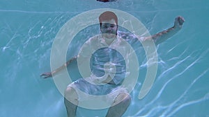 Man in clothes wallows underwater.