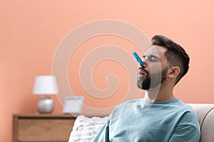 Man with clothespin suffering from runny nose at home