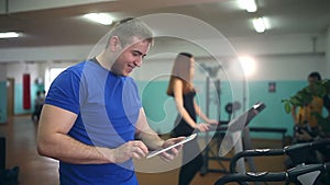 Man coach in the gym girl with the tablet on the treadmill fitness, healthy lifestyle, sport