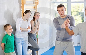 Man coach shows family students technique of performing painful modus with help of wringing hand photo