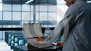 Man coding on data center, testing failover scenarios using notebook