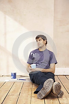 Man With Coffee Mug On Floor Of Unrenovated Room