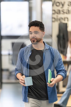 Man with coffee and phone in a modern office.