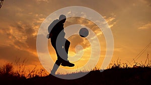 Man coins a ball European the football soccer freestyle silhouette at sunset sunlight. man beats chasing ball football