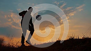 Man coins a ball European the football soccer freestyle silhouette at sunset sunlight. man beats chasing ball football