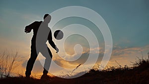 Man coins a ball European the football soccer freestyle silhouette at sunset sunlight. man beats chasing ball outdoors
