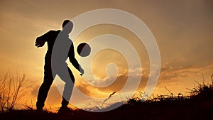 Man coins a ball European the football soccer freestyle silhouette at sunset sunlight. man beats chasing outdoors ball