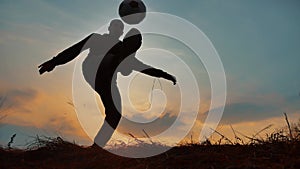 Man coins a ball European the football soccer freestyle silhouette at sunset sunlight. man beats outdoors chasing ball