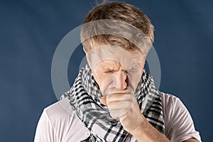 Man with cold and flu illness suffering from a headache and cough. Blue background
