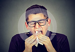 Man with cold sneezing in tissue