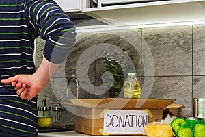 Man collect food in donation cardboard box in kitchen