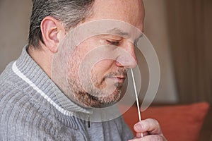 man collecting nasal mucus sample from nose with cotton swab for covid-19 coronavirus self testing at home photo