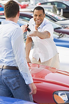 Man collecting new car from salesman