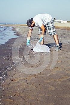 Volunteer collecting plastics that pollute the sea photo