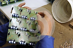 A man collects a printed circuit board. The worker solders the radio components and assembles the finished device. Manual assembly