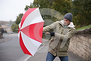 Man with colorful umbrella caught in gust of wind on street