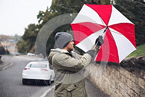 Man with colorful umbrella caught in gust of wind on street